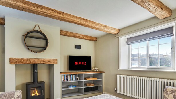 Una sala de estar acogedora con chimenea, una estantería, un televisor y un ventanal con vistas.