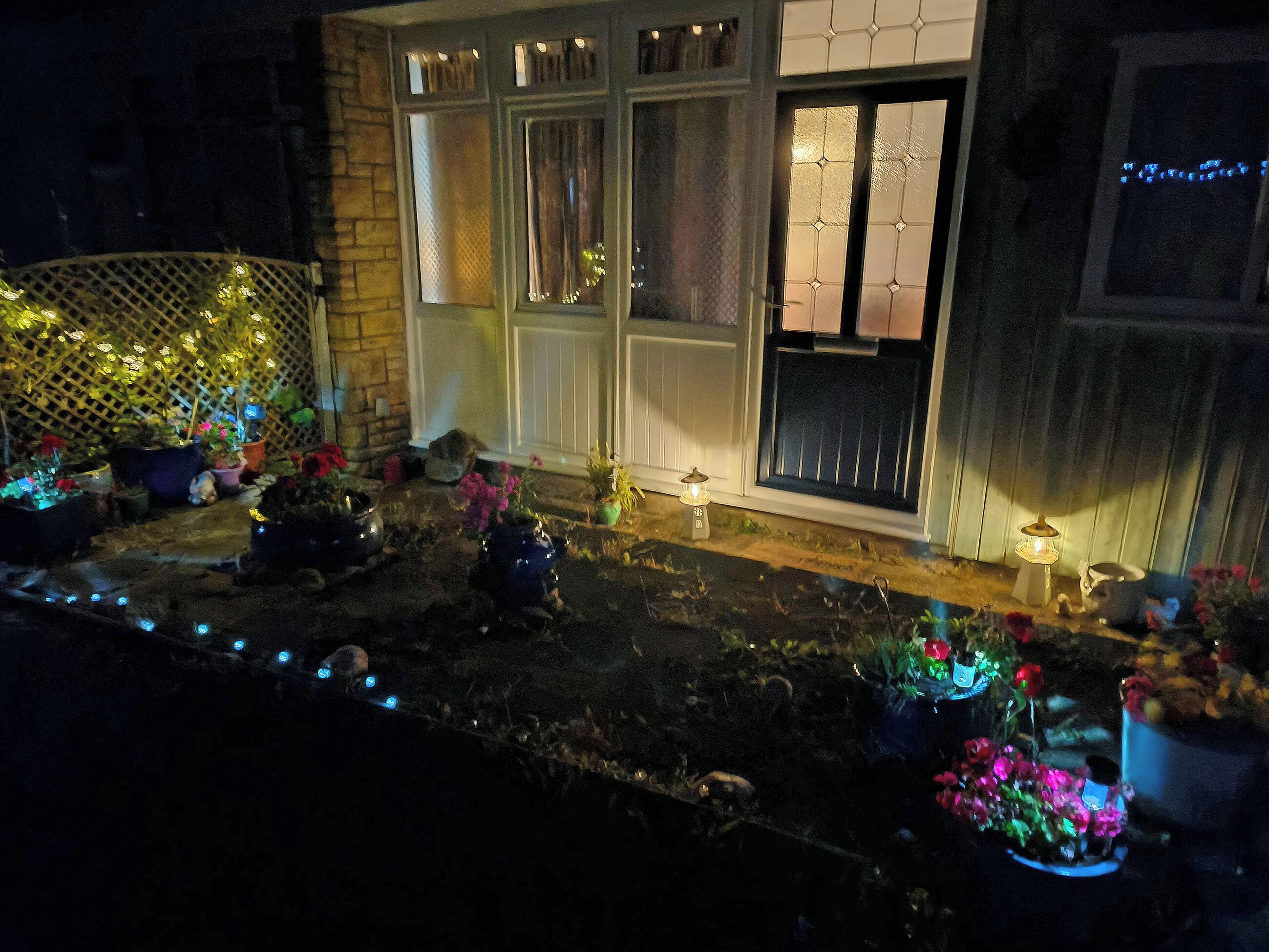 Una casa con porche delantero decorado con plantas en macetas y luces colgantes.