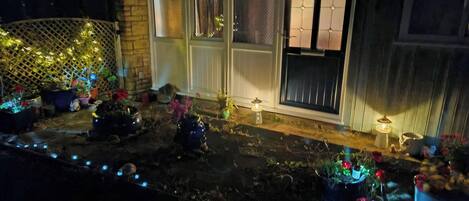 Una casa con porche delantero decorado con plantas en macetas y luces colgantes.