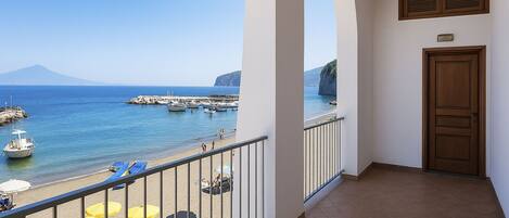 A balcony with a view of the sea, a door, and a tiled floor.