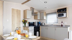 Cozinha moderna com área de refeições, com fogão, micro-ondas e armários.