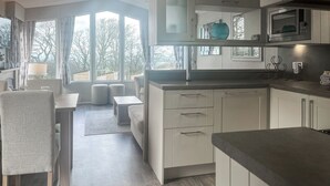 Et moderne køkken med hvide skabe, en mikrobølgeovn og et spiseområde med bord og stole.