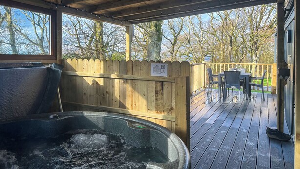 A hot tub area with a wooden deck and a view of trees. - Herdwick Lodge - UK51383 (Brocklebank, near Caldbeck and Uldale)