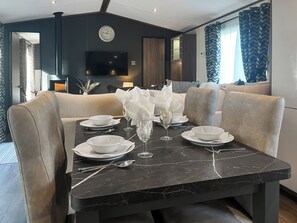 Een eetgedeelte met een marmeren tafel gedekt voor vier personen, omringd door beige fauteuils.