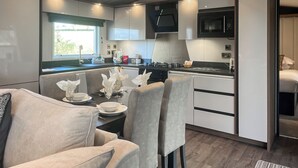A modern kitchen with a dining area, equipped with a stove, microwave, and various appliances. - Herdwick Lodge - UK51383 (Brocklebank, near Caldbeck and Uldale)