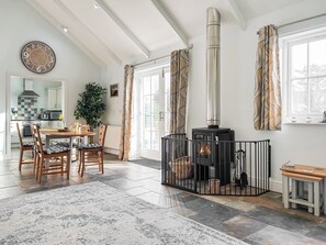 A cozy living room with a fireplace, a dining area, and a kitchen visible through an open door. - 3 bedroom accommodation in Helston (Helston)