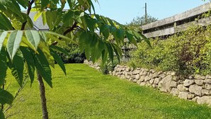 Ett välskött grönområde med en stenmur och ett träd i förgrunden.