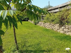 A well-maintained grassy area with a stone wall and a tree in the foreground. - 3 bedroom accommodation in Helston (Helston)