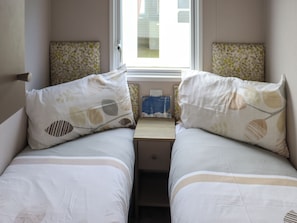 Une chambre double avec deux lits, une petite table et une fenêtre donnant sur des immeubles.