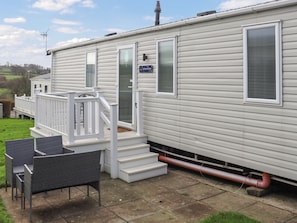 Une maison mobile dotée d’une terrasse, de meubles d’extérieur et d’une cheminée.