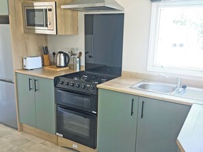 Une cuisine équipée d’un four à micro-ondes, d’une cuisinière, d’un four et d’un évier.
