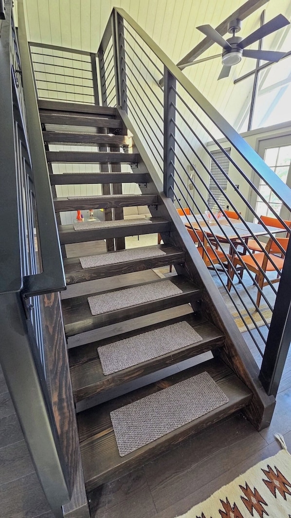 Eine Holztreppe mit Metallgeländern und einem Deckenventilator.
