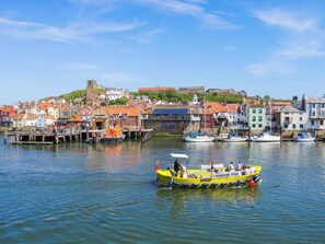 A harbor with boats, a dock, and a town with buildings. - Old Steamship Quarters (Whitby)