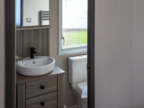A bathroom with a white sink, a mirror, a towel hanging on the wall, and a window with blinds. - Lockwood 47 - UK51393 (Narberth)