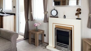 A living room with a fireplace, a clock, and a small table with flowers. - Ballagan Lodge 2 - UK51397 (Inverness)
