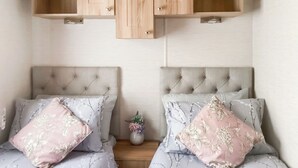 Two twin beds with tufted headboards, a small vase with flowers, and wooden cabinets above. - Ballagan Lodge 2 - UK51397 (Inverness)