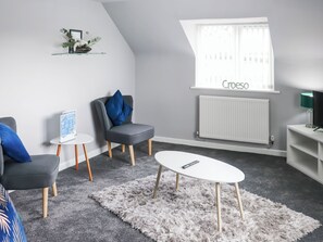 A modern living room with a grey sofa, a blue armchair, a white coffee table, and a white shag rug. - 2 bedroom accommodation in Narberth (Narberth)