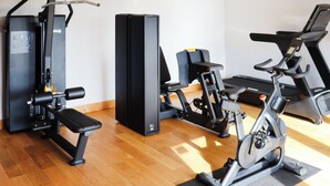 Ein Fitnessstudio mit Laufbändern, Krafttrainingsgeräten und einer Trainingsbank.