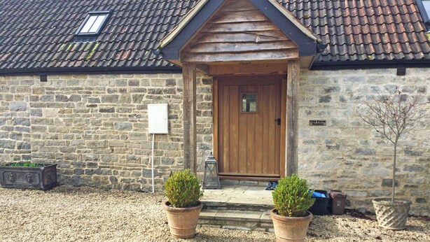 A stone building with a wooden door, two potted plants, and a gravel driveway. - 1 bedroom accommodation in South Barrow, near Yeovil (Yeovil)