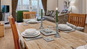 A dining area with a wooden table set for four, a green candle, and a painting of a cow on the wall. - 1 bedroom accommodation in South Barrow, near Yeovil (Yeovil)