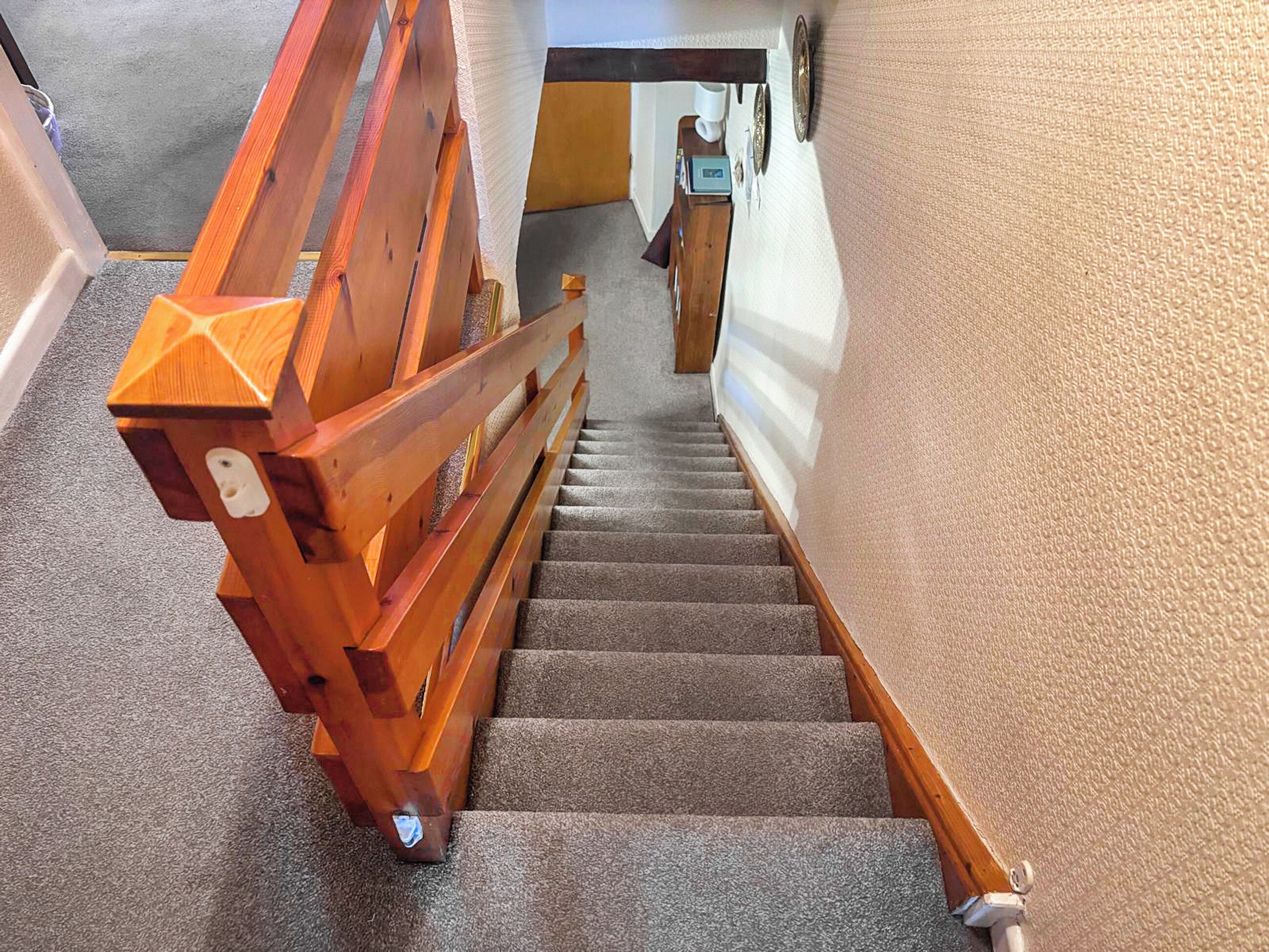 A wooden staircase with carpeted steps leading to a landing.