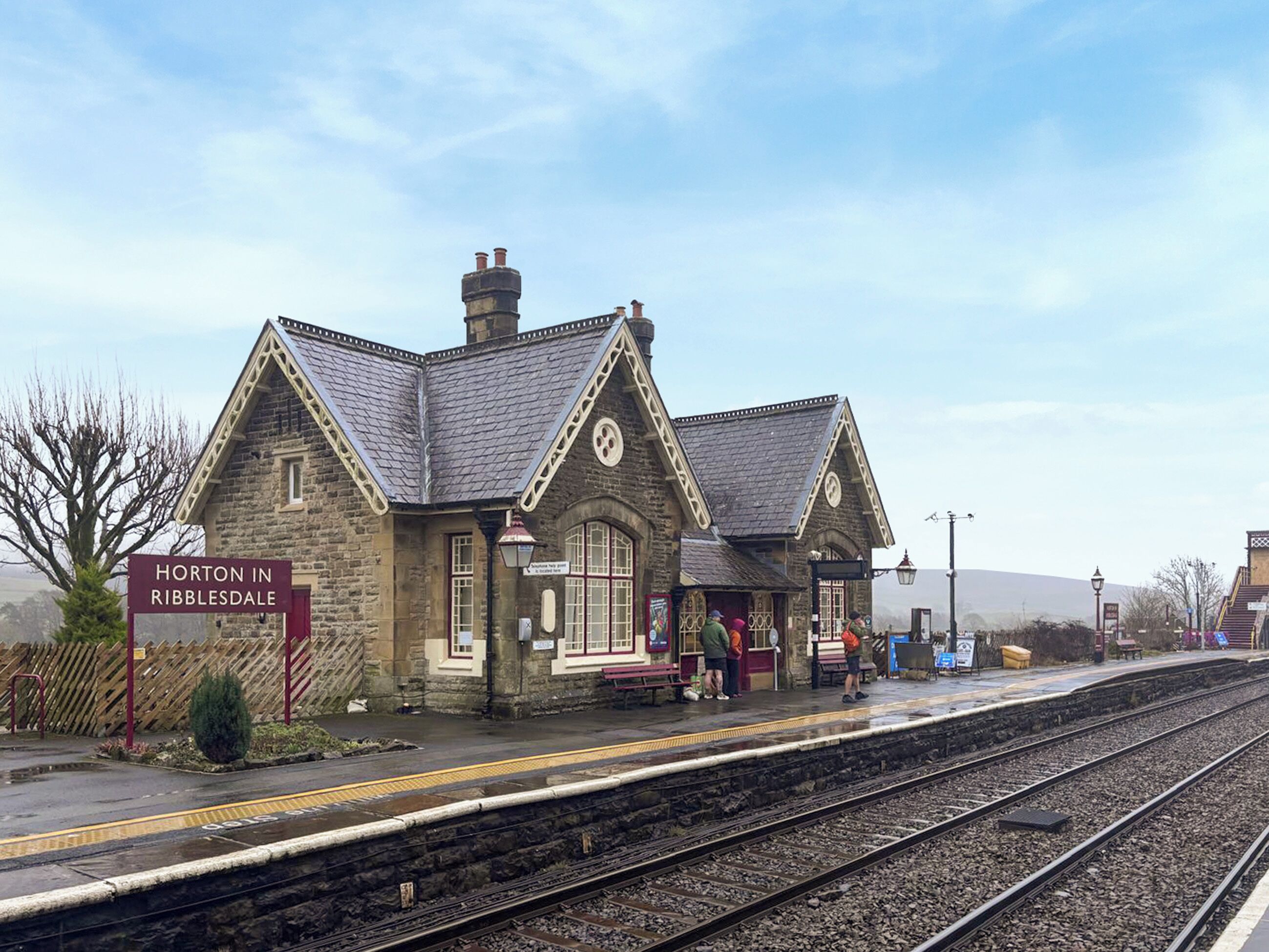 Un bâtiment en pierre avec une enseigne indiquant « Horton-in-Ribbledale », situé près d’une gare.