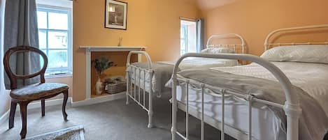 Ein Schlafzimmer mit zwei Betten, einem Sessel, einem Fenster und einem Gemälde an der Wand.