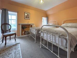 A bedroom with two beds, a chair, a window, and a painting on the wall. - Elegant, homey Anstruther apartment with sea views and fresh coastal air. (Anstruther)