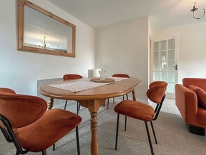 A dining area with a round table, six chairs, a chandelier, and a large mirror on the wall. - Elegant, homey Anstruther apartment with sea views and fresh coastal air. (Anstruther)