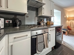 A modern kitchen with white cabinets, a stainless steel range hood, and a coffee maker. - Elegant, homey Anstruther apartment with sea views and fresh coastal air. (Anstruther)