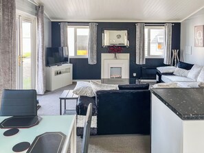 Een moderne woonkamer met een bank, een televisie, een open haard en een eethoek.