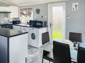 A compact kitchen with a washing machine, a microwave, and a coffee maker. - 3 bedroom accommodation in Corton (Corton)