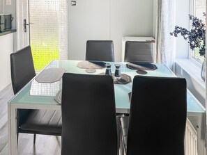A modern dining area with a glass table, black chairs, and a view of the outdoors.