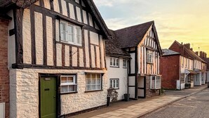 A row of traditional half-timbered houses with a green door, white walls, and a clear sky. - 1 bedroom accommodation in Bosbury (Bosbury)