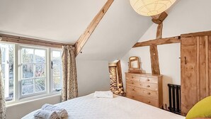 A bedroom with a large bed, a dresser, a mirror, and a window with curtains. - 1 bedroom accommodation in Bosbury (Bosbury)