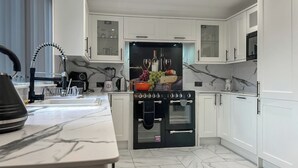 Une cuisine moderne avec des meubles blancs, une cuisinière noire et un plan de travail en marbre.