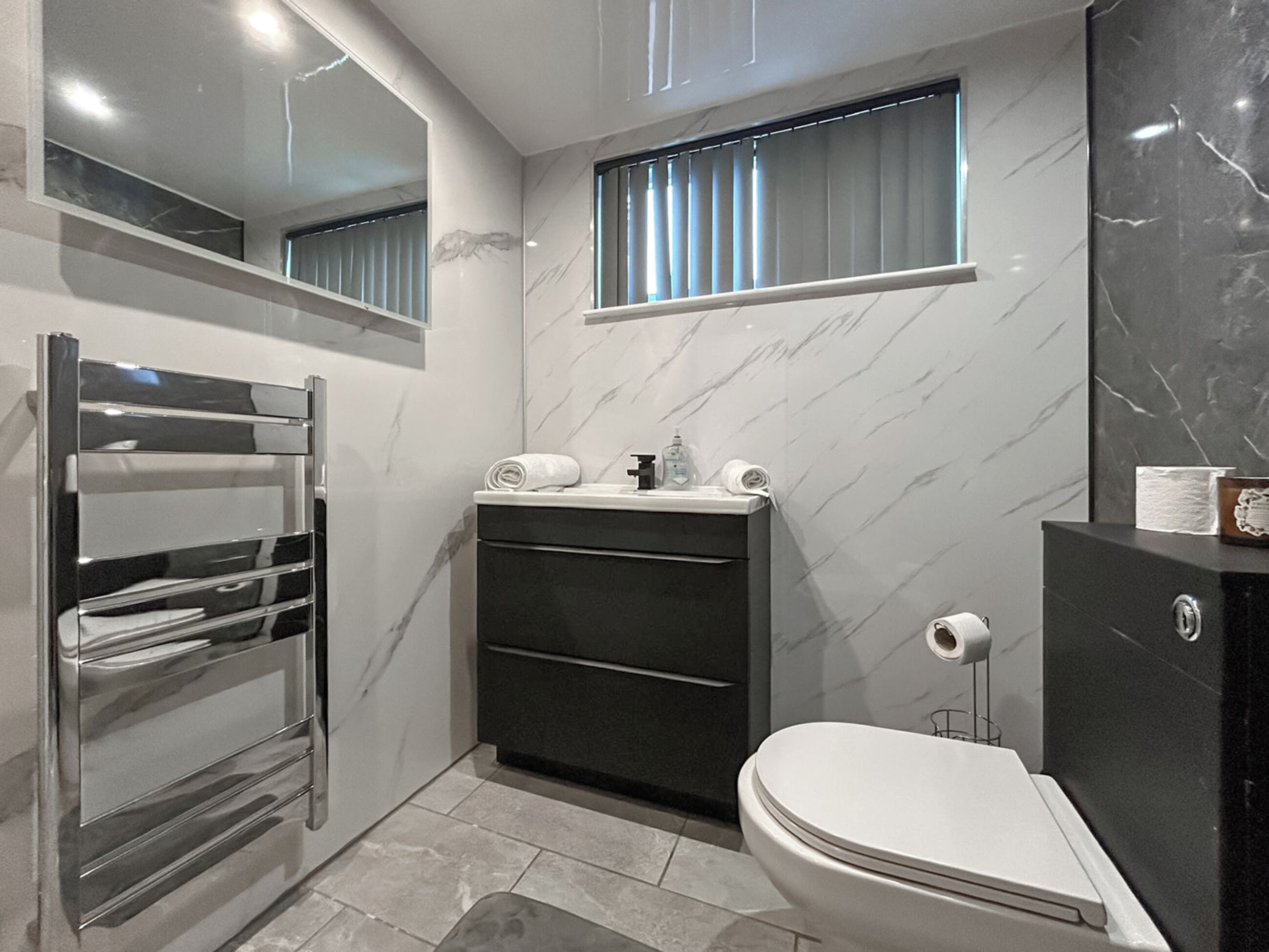 Ein modernes Badezimmer mit integriertem Waschbecken, Toilette und Handtuchhalter.