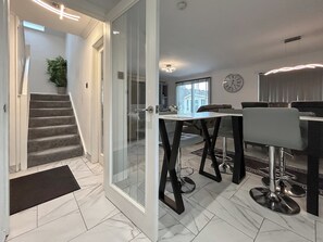 Et moderne interiør med trappe, spiseområde med barstole og et stort ur på væggen.