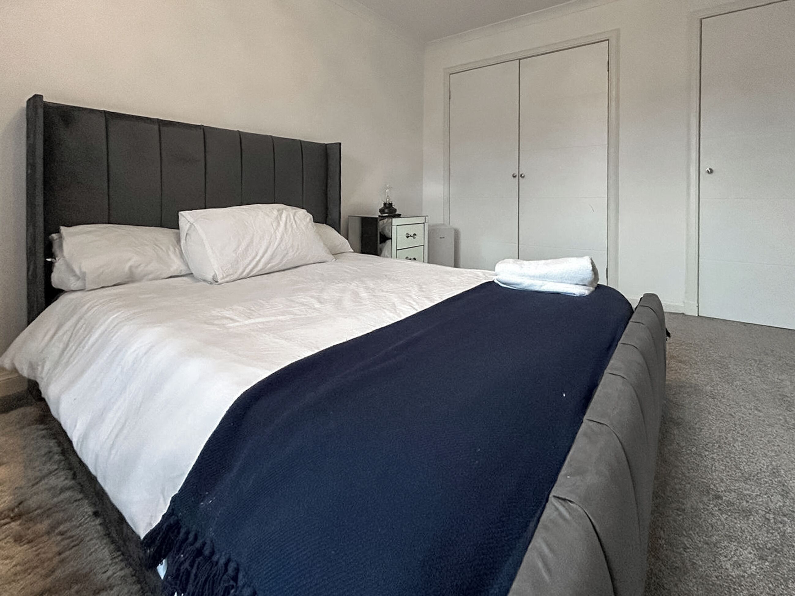 Une chambre à coucher comprenant un lit, une table de chevet, une commode et une armoire.