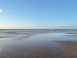 Uma praia com areia molhada e ondas suaves.