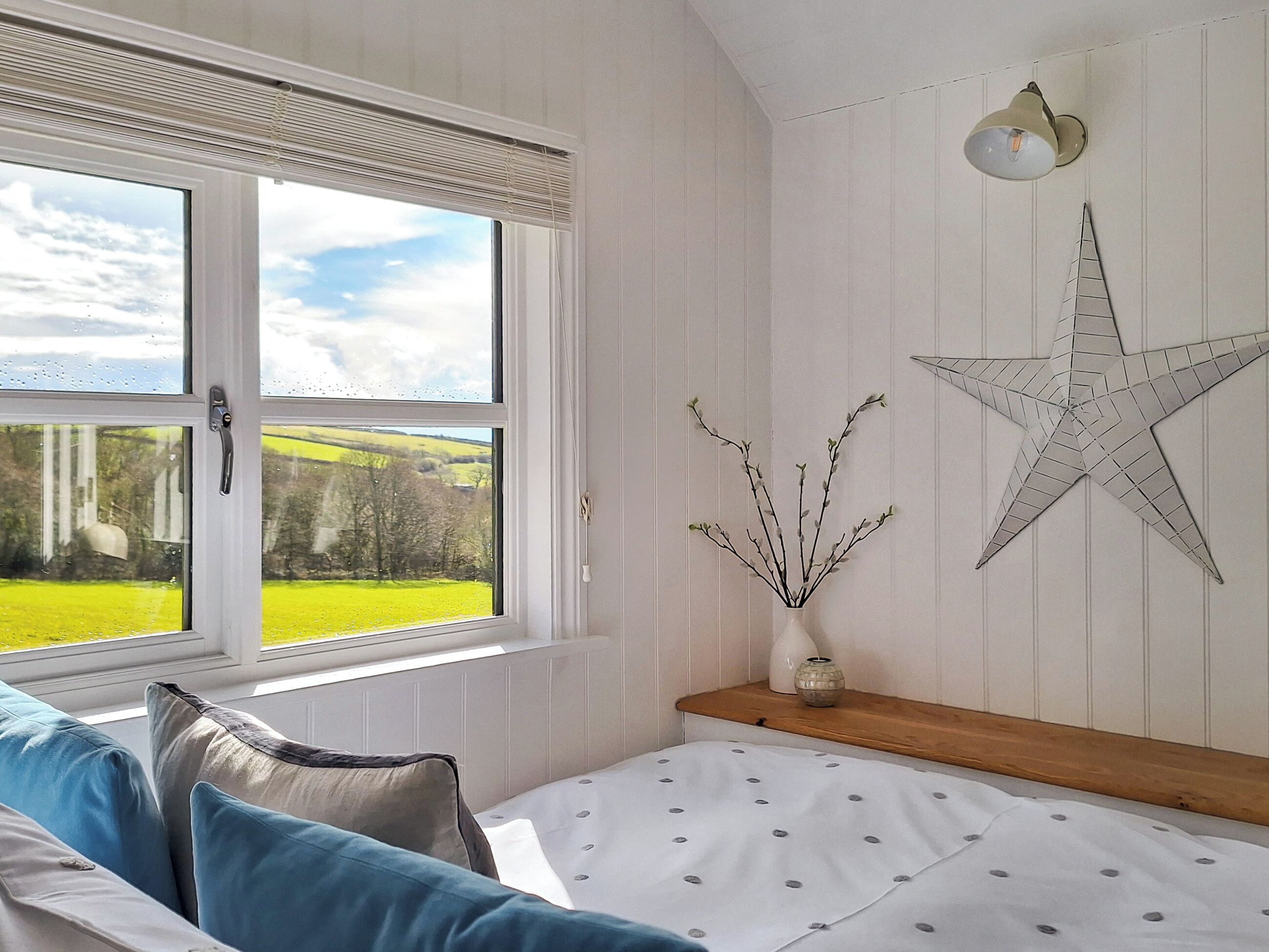 A bedroom with a large window, a star decoration, and a vase with branches.