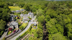 A rural village with stone houses, a winding road, and lush greenery.