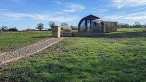 Une construction en bois d’un seul étage, dotée d’un toit incurvé, d’une terrasse et d’une entrée clôturée.