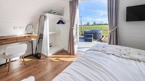 Une chambre à coucher comprenant un lit, un bureau, une chaise, un miroir et une vue sur l’extérieur.