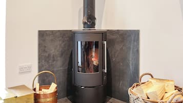 Uma lareira a lenha com porta de vidro, um balde de metal com lenha e uma cesta de vime cheia de toras.