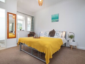 A bedroom with a bed, a bedside table, a lamp, a mirror, and a window. - Bay Tree View - UK51428 (Paignton)