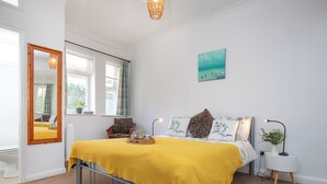 A bedroom with a bed, a bedside table, a lamp, a mirror, and a window. - Bay Tree View - UK51428 (Paignton)