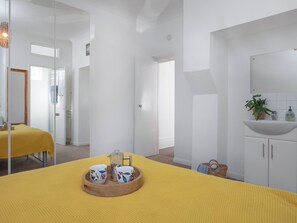 A bright room with a yellow bedspread, a wooden tray with cups and a teapot, and a white sink with a plant. - Bay Tree View - UK51428 (Paignton)