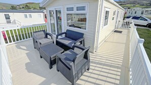 Ein Wohnmobil mit einer Terrasse, ausgestattet mit Korbmöbeln und Blick auf die umliegende Landschaft.