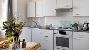 A modern kitchen with white cabinets, a built-in oven, and a countertop with various kitchen items. - A comfortable first-floor apartment for two with lovely sea views. (Paignton)